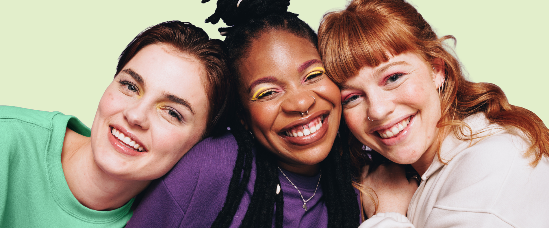 Group shot of three smiling female teens leaning on each other smiling