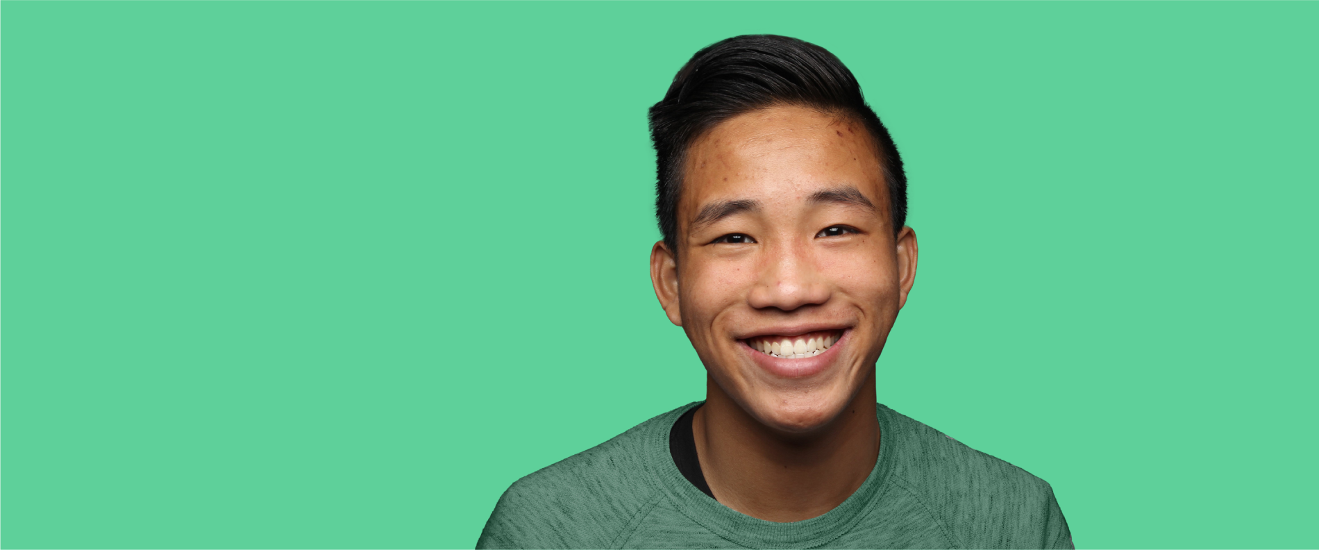 Younger male teenager with visible acne smiling confidently at camera.