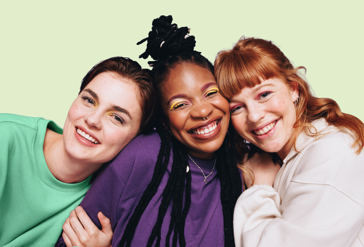Group shot of three smiling female teens resting their heads together.