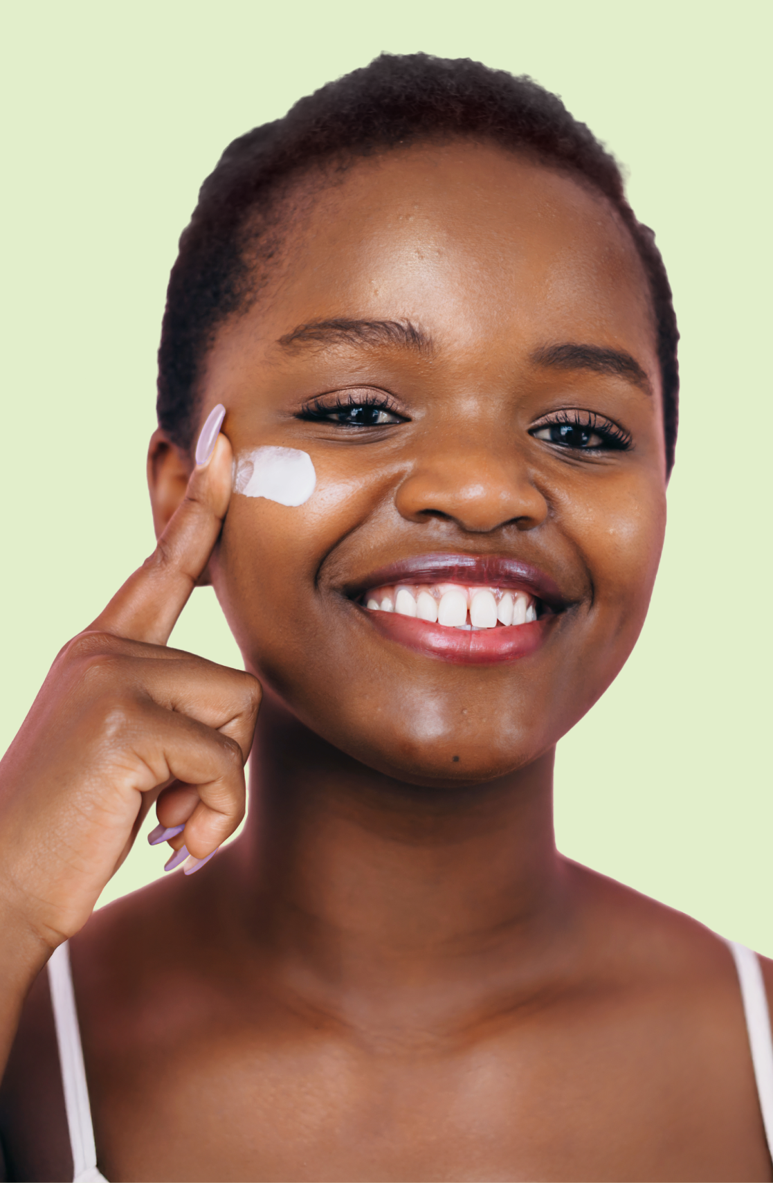 Close up of a older male teenager applying acne cream to his cheek as he smiles and looks off camera.
