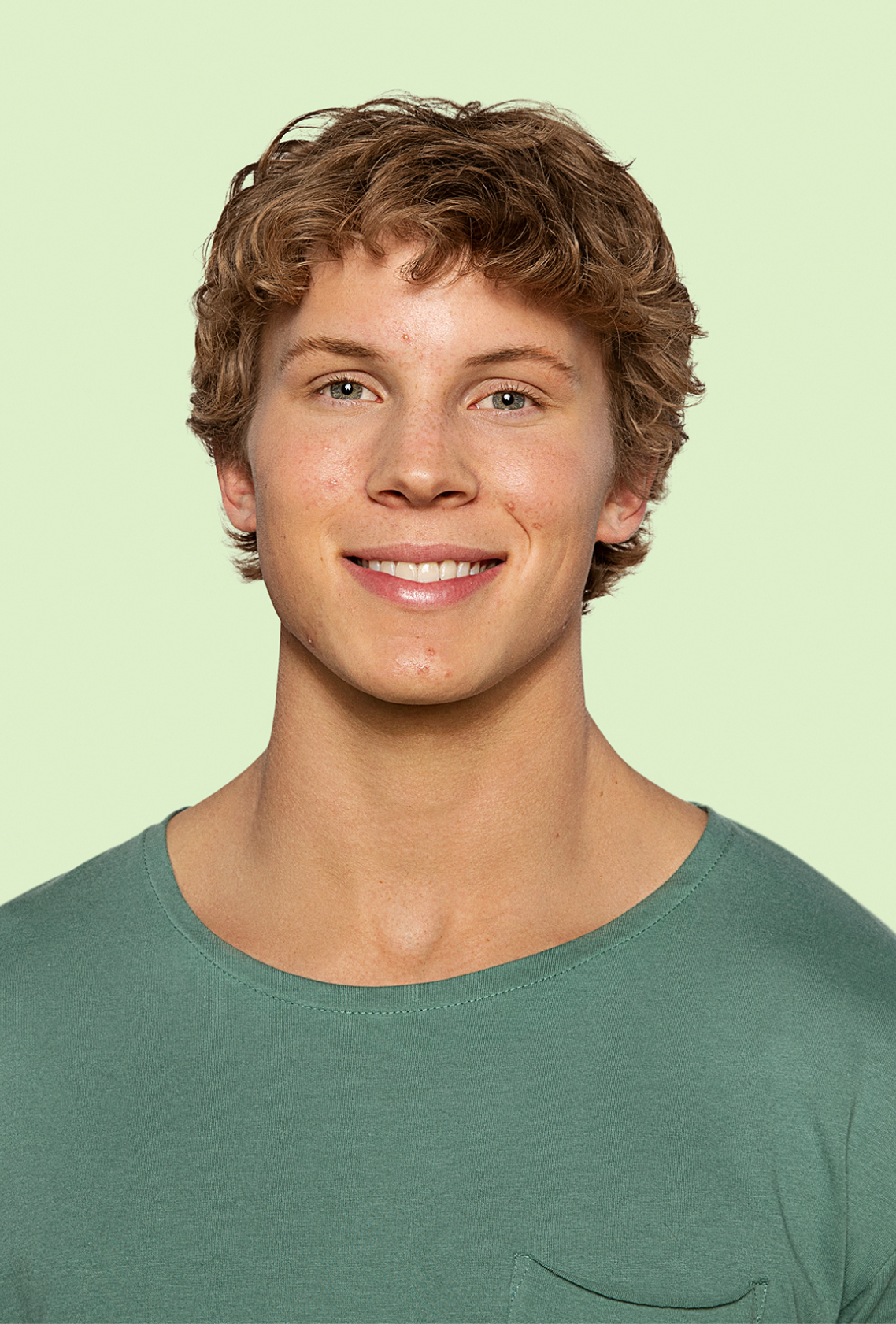 Older male teen with visible acne confidently smiling at camera.